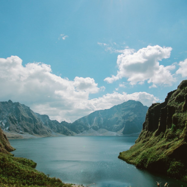 Der Pinatubo-See umgeben von grünen Bergen unter einem bewölkten Himmel.