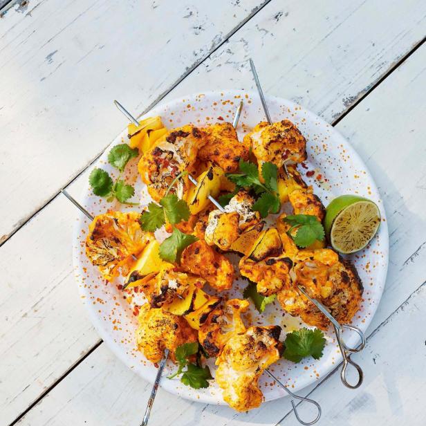 Blumenkohlspieße mit Limetten und Koriander auf einem Teller.