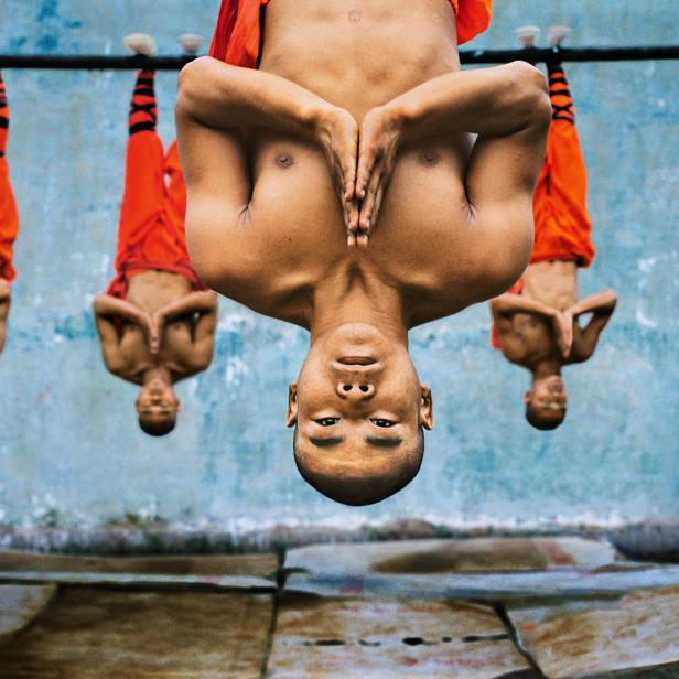 Shaolin Mönche hängen kopfüber an einer Stange.