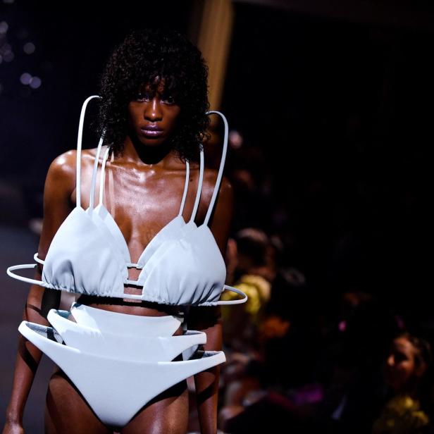 Eine Frau präsentiert ein futuristisches, weißes Bikini-Ensemble auf dem Laufsteg.