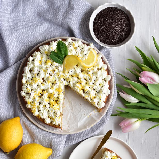 Ein Zitronen-Mohnkuchen mit Schlagsahne und Zitronenzesten, dazu Tulpen und Zitronen.