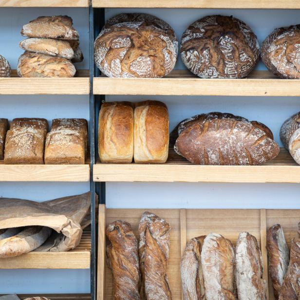 Regale in einer Bäckerei sind mit verschiedenen Brotsorten gefüllt.