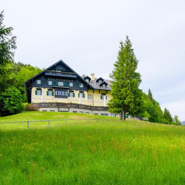 Der KnappenHof liegt auf einer grünen Wiese mit Blick auf die Berge.