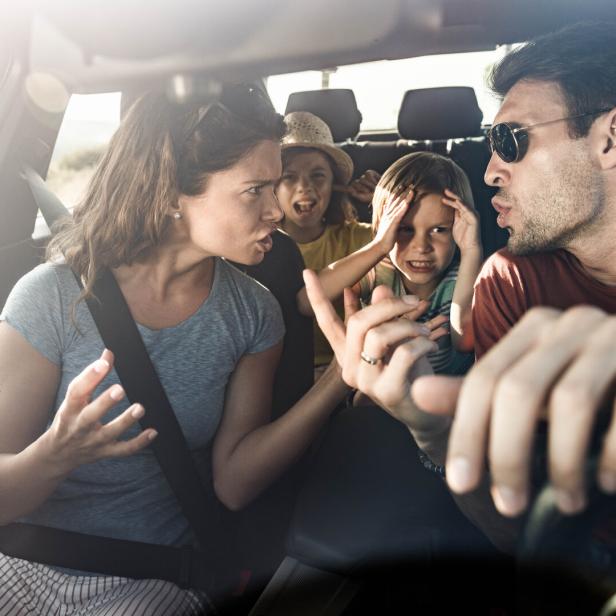 Eltern streiten im Auto, Kinder sitzen auf der Rückbank und halten sich die Ohren zu, Krise im Urlaub.