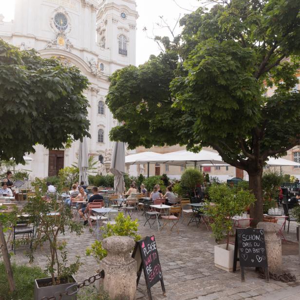 Ein belebtes Straßencafé vor einer barocken Kirche in Melk, Österreich.