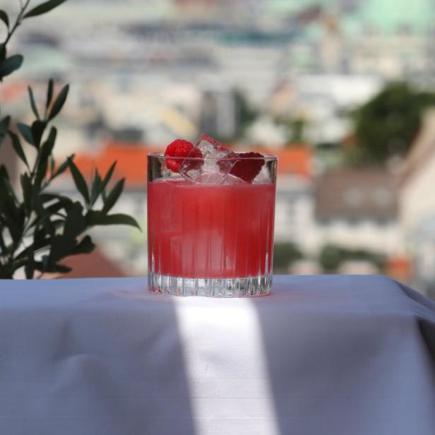 Ein Himbeer-Cocktail mit Eiswürfeln auf einem Tisch mit Blick auf Wien.