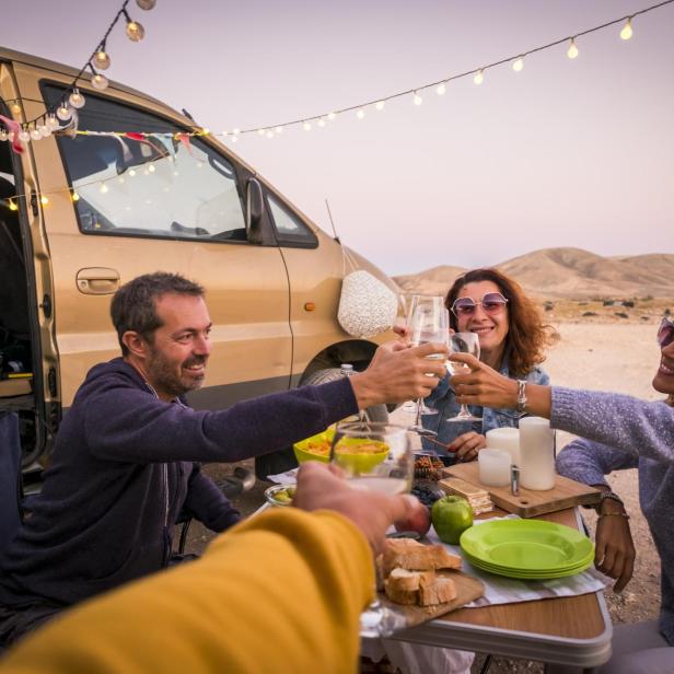 Freunde stoßen bei einem Campingausflug mit Wein an.