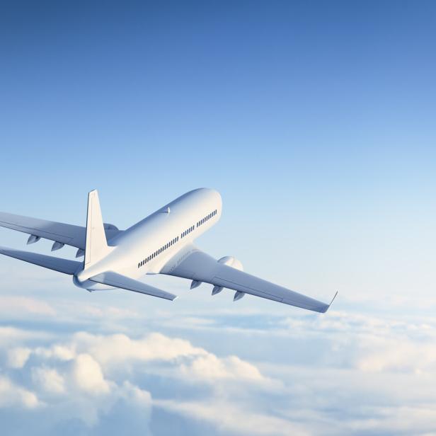 Ein weißes Flugzeug fliegt über den Wolken.