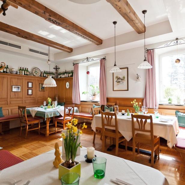 Ein traditionell eingerichtetes Restaurant mit Holzbalken und gedeckten Tischen.