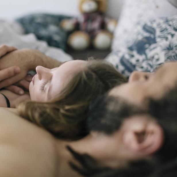 Ein Paar liegt eng umschlungen im Bett.