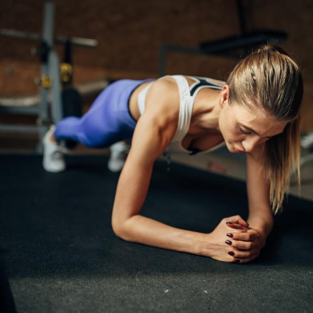 Eine Frau macht im Fitnessstudio eine Plank-Übung.