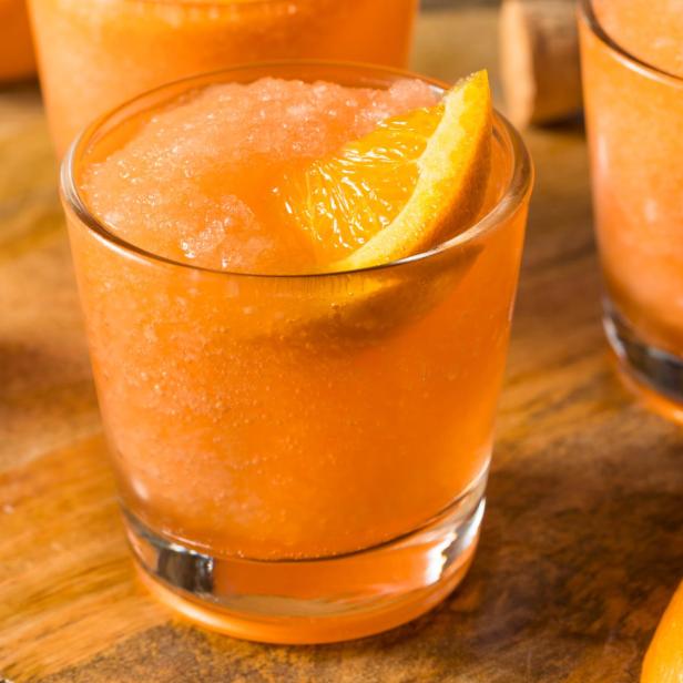 Ein gefrorener Aperol Spritz mit einer Orangenscheibe als Dekoration.