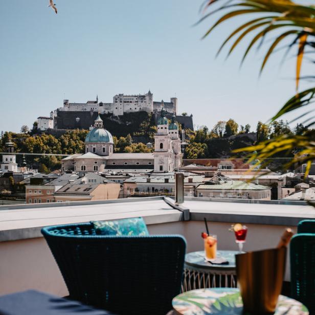 Blick von einer Dachterrasse auf die Festung Hohensalzburg und die Stadt Salzburg.