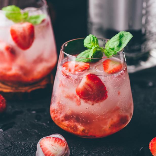 Ein erfrischender Cocktail mit Erdbeeren und Minze, serviert in einem Glas mit Eiswürfeln.