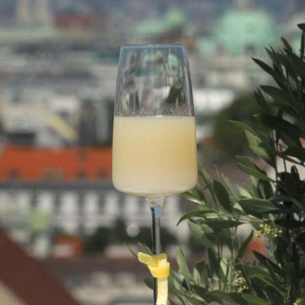 Ein Glas Mimosa mit Zitronenzeste auf einem Tisch mit Blick auf eine Stadt.
