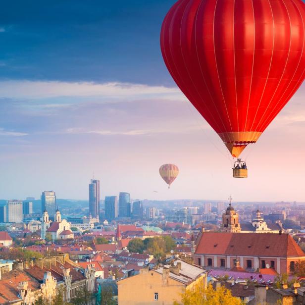 Ein roter Heißluftballon über der Stadt Vilnius bei Sonnenaufgang.