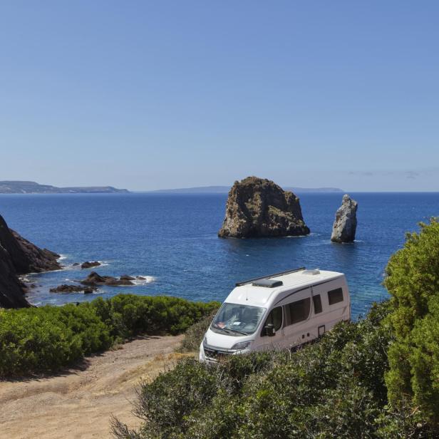 Ein Wohnmobil steht an der Küste mit Blick auf das Meer und Felsen.
