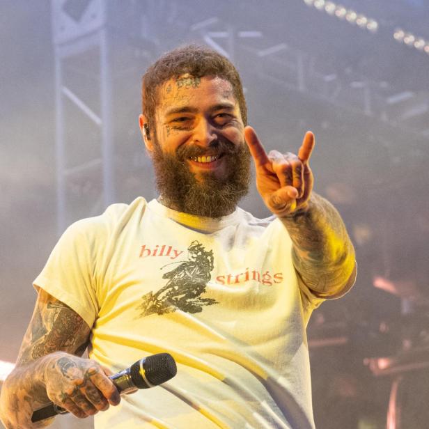 Post Malone lächelt und macht eine Geste mit seiner Hand.