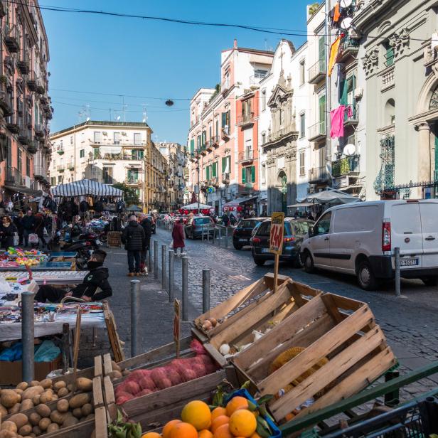 Ein belebter Straßenmarkt in Neapel mit Obst, Gemüse und verschiedenen Waren.