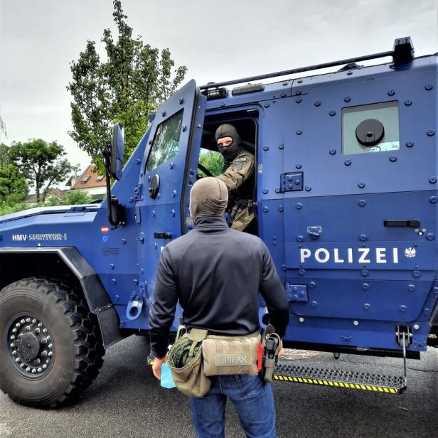 Zwei Polizisten stehen vor einem blauen HMV Survivor I gepanzerten Fahrzeug.