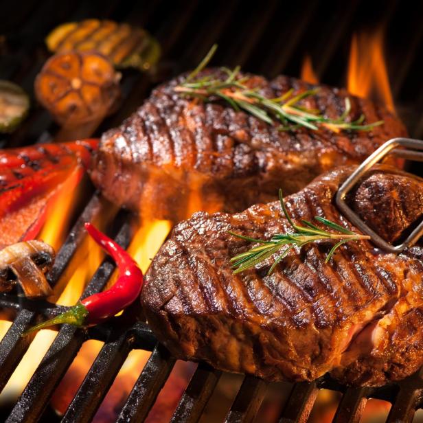 Zwei Steaks und Gemüse werden auf einem Grill zubereitet.