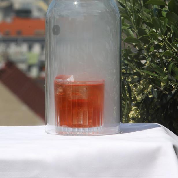 Ein rauchiger Cocktail unter einer Glasglocke mit Blick auf eine Stadt.