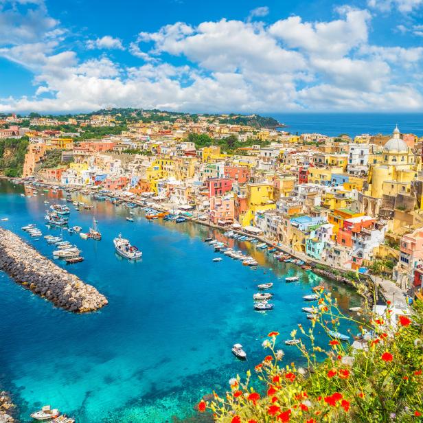 Blick auf die farbenfrohe Küstenstadt Procida in Italien mit zahlreichen Booten im Hafen.