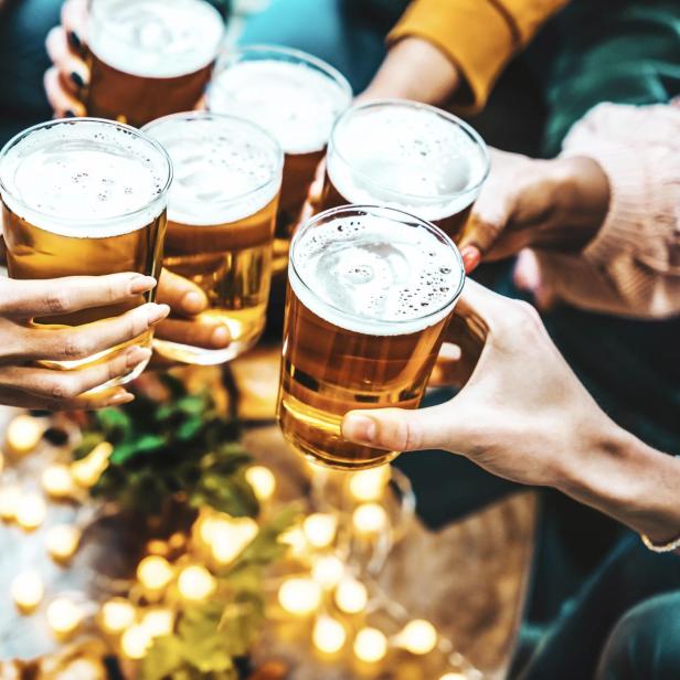 Eine Gruppe von Menschen stößt mit Bier in einem Restaurant an.