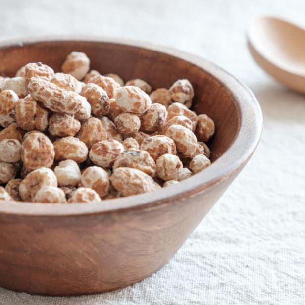 Ein Holzlöffel und eine Schale mit Erdmandeln, einem Superfood.