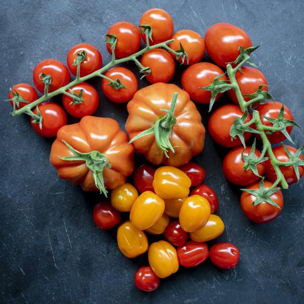 Verschiedene Tomatensorten liegen auf einer dunklen Oberfläche.