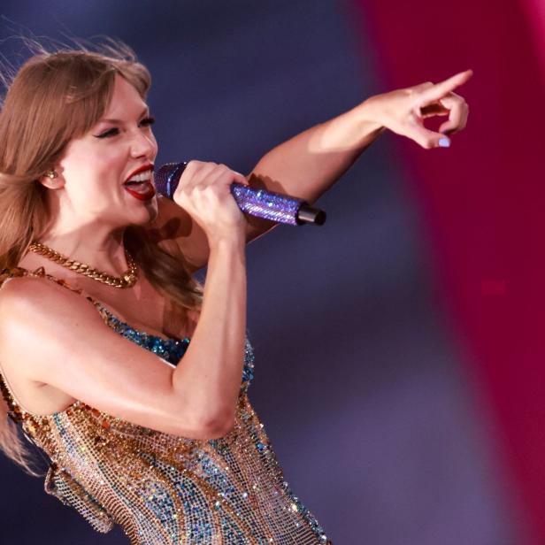 Taylor Swift singt während eines Konzerts und zeigt mit dem Finger.