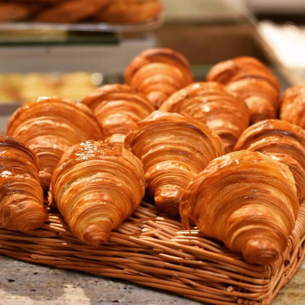 Eine Auswahl goldbrauner Croissants in einem geflochtenen Korb.