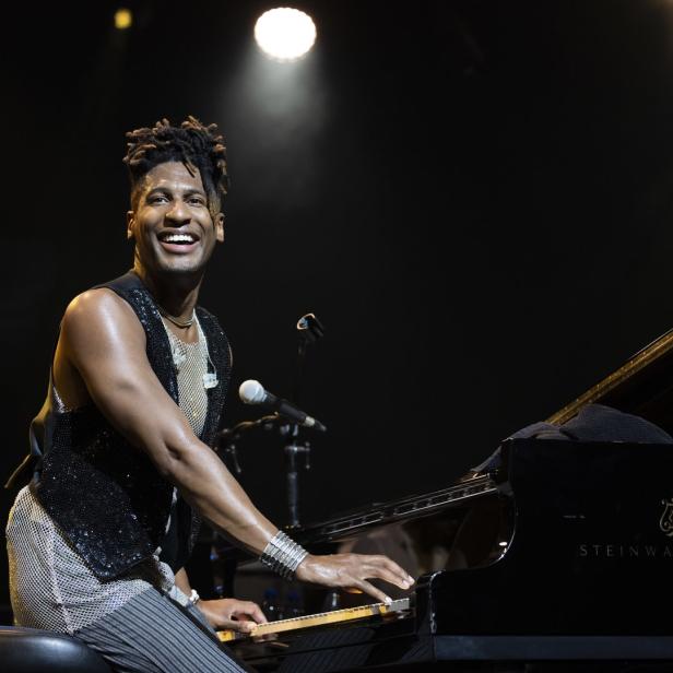 Jon Batiste spielt auf einem Steinway & Sons Klavier und lächelt.