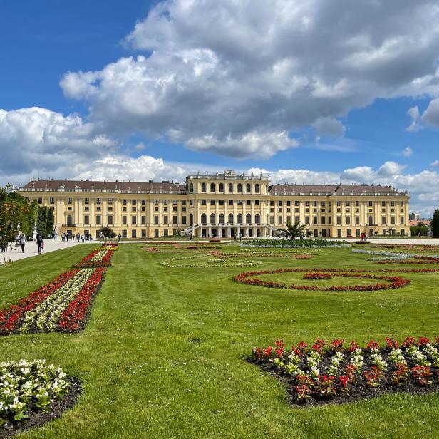 Das Schloss Schönbrunn mit seinem weitläufigen Garten unter einem bewölkten Himmel.