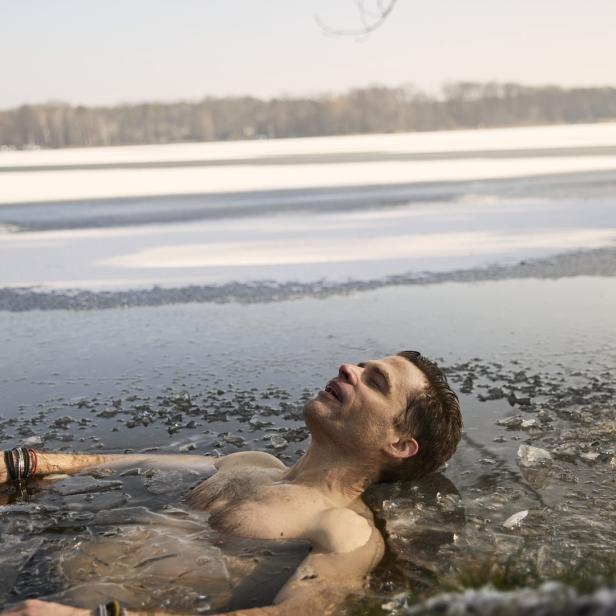 Ein Mann liegt im eisigen Wasser eines Sees.