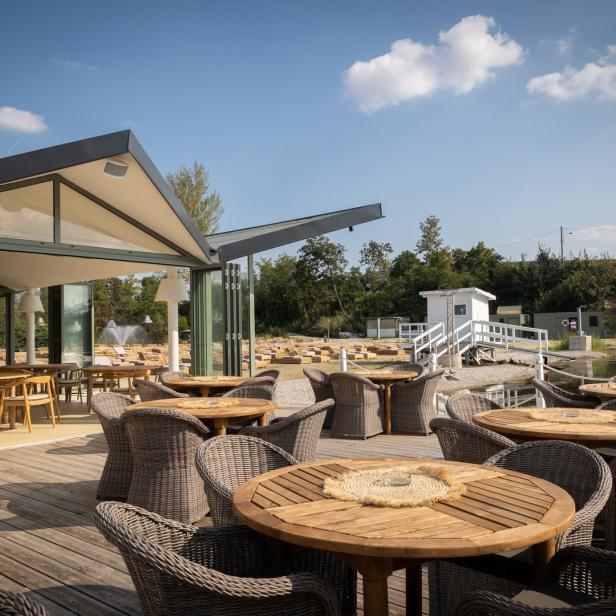Ein Restaurant mit Tischen und Stühlen im Freien an einem sonnigen Tag.