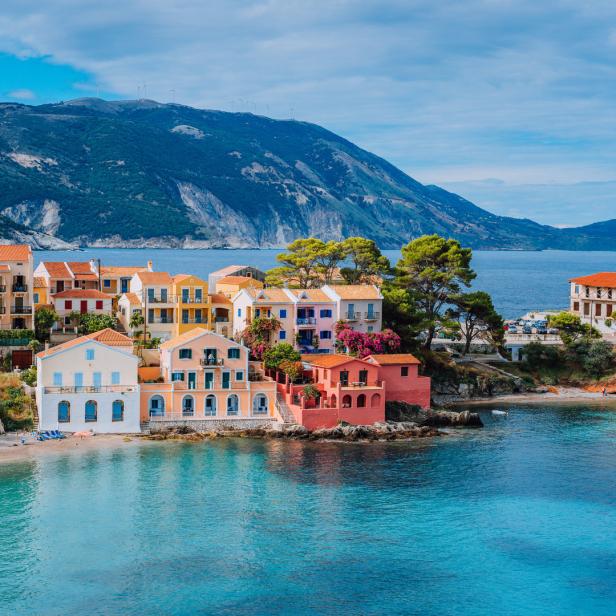 Blick auf die bunten Häuser von Assos auf Kefalonia, Griechenland, mit dem Ionischen Meer im Vordergrund.