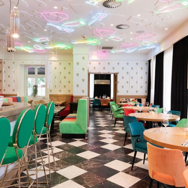 Ein farbenfrohes Restaurant mit Schachbrettboden und Neon-Dekorationen an der Decke.