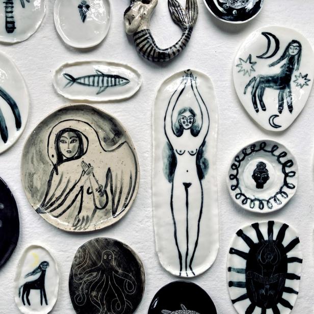 Verschiedene kleine, handbemalte Keramikteller mit Motiven wie Meerjungfrauen, Fabelwesen und abstrakten Figuren liegen auf einem weißen Hintergrund.