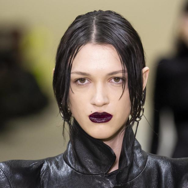 Eine Frau mit dunklem Lippenstift und einem schwarzen Lederjackett.