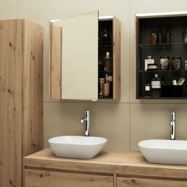 Zwei Waschbecken mit Spiegel- und Holzschränken in einem Badezimmer.