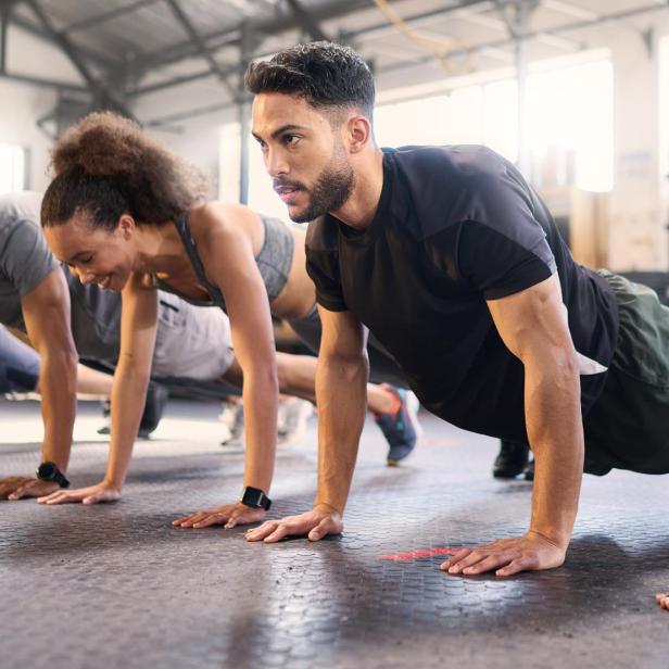Eine Gruppe von Menschen macht Liegestütze in einem Fitnesskurs.