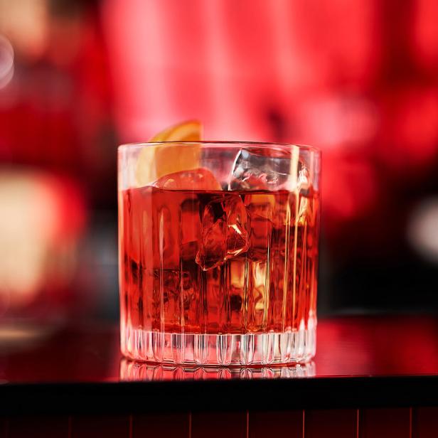 Ein Glas Negroni mit Eiswürfeln und einer Orangenscheibe, beworben für die Campari Negroni Week.