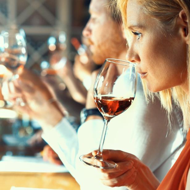 Frau riecht an einem Glas Rotwein.