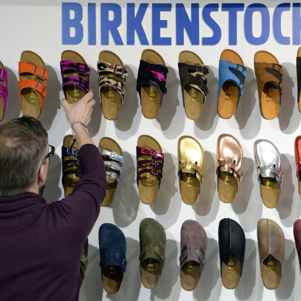 Ein Mann betrachtet eine Wand mit verschiedenen Birkenstock-Sandalen.