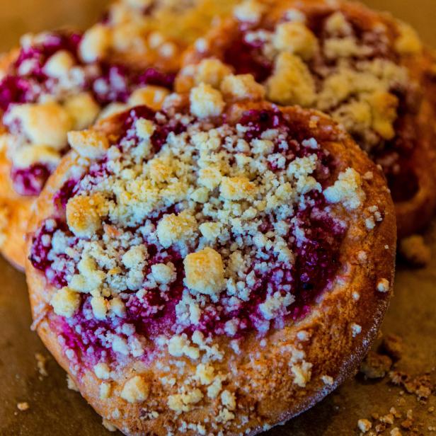 Drei runde Kuchen mit roter Füllung und Streuseln liegen auf einem Tisch.