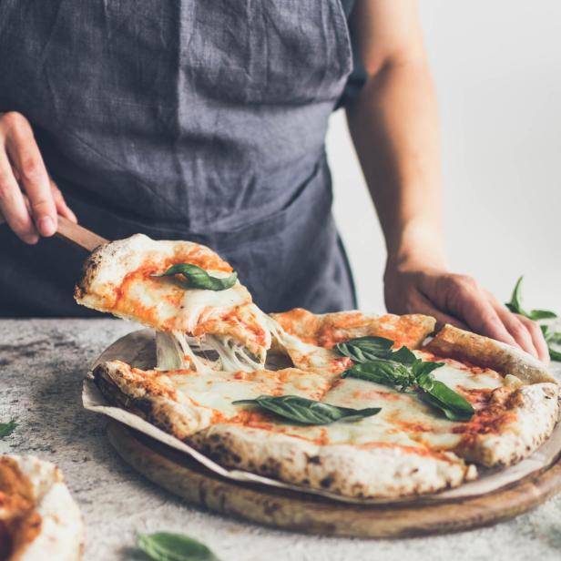 Mann serviert Pizza, Käse zieht Fäden.