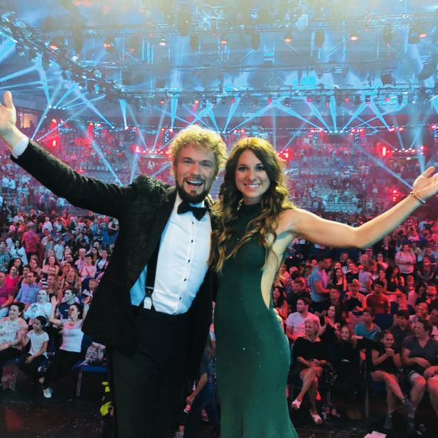 Thommy Ten und Amélie van Tass stehen auf einer Bühne vor Publikum.