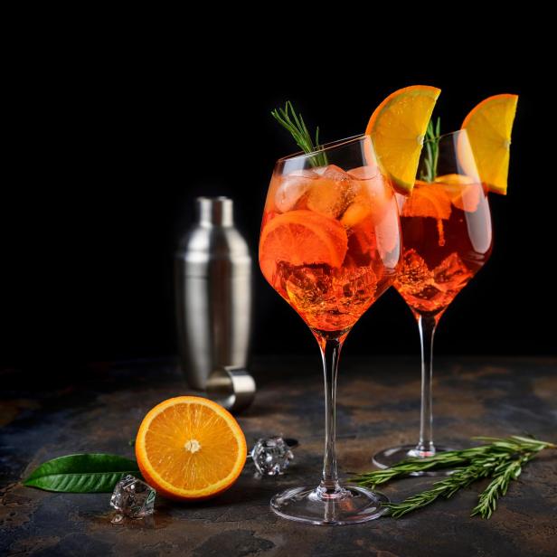 Zwei Gläser Aperol Spritz mit Orangenscheiben und Eiswürfeln.