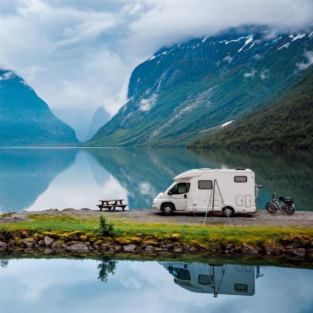 Wohnmobil vor Panorama mit einem See und Bergen.